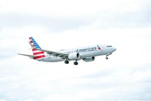  American Airlines . Aircraft flying against a bright, cloudy sky, showcasing aviation excellence.