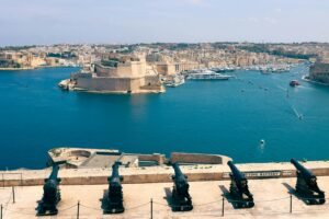 Military Cruise A stunning view of Valletta's harbor and fortifications with historic cannons in Malta.