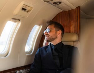 First Class Flying deals A man in a suit and sunglasses enjoys a luxurious flight in a private jet.