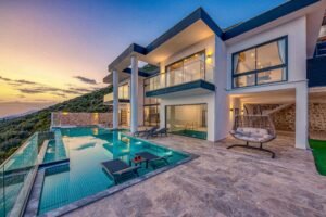 Holiday Travel Elegant modern villa featuring an infinity pool and scenic hill views during sunset.