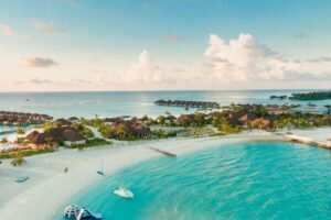 Carribean A stunning aerial view of a tropical Maldives beach with clear turquoise waters and resorts along the shore.
